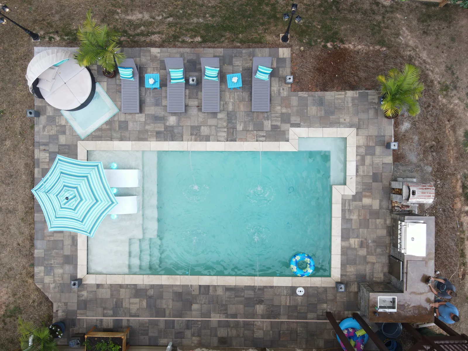 Drone view of a finished RutherfordMade pool with umbrella seating and a paver patio