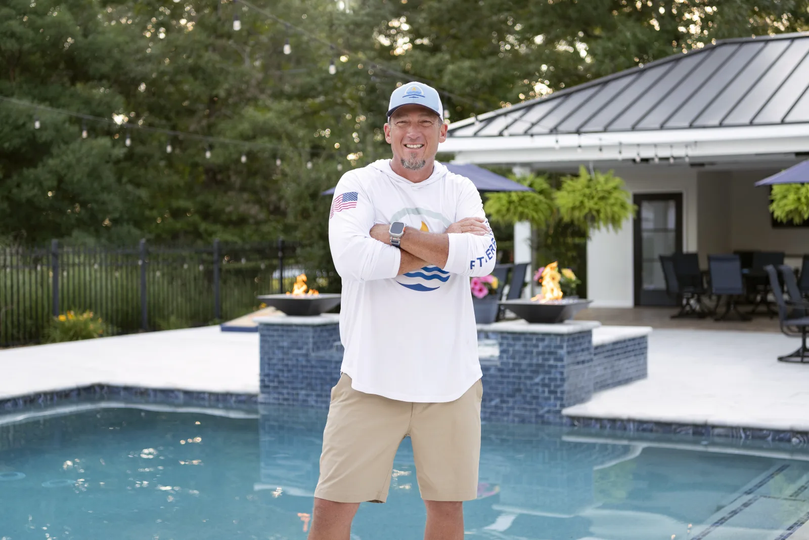 Scott Rutherford standing in front of a just-completed RutherfordMade pool with fire bowls and cabana