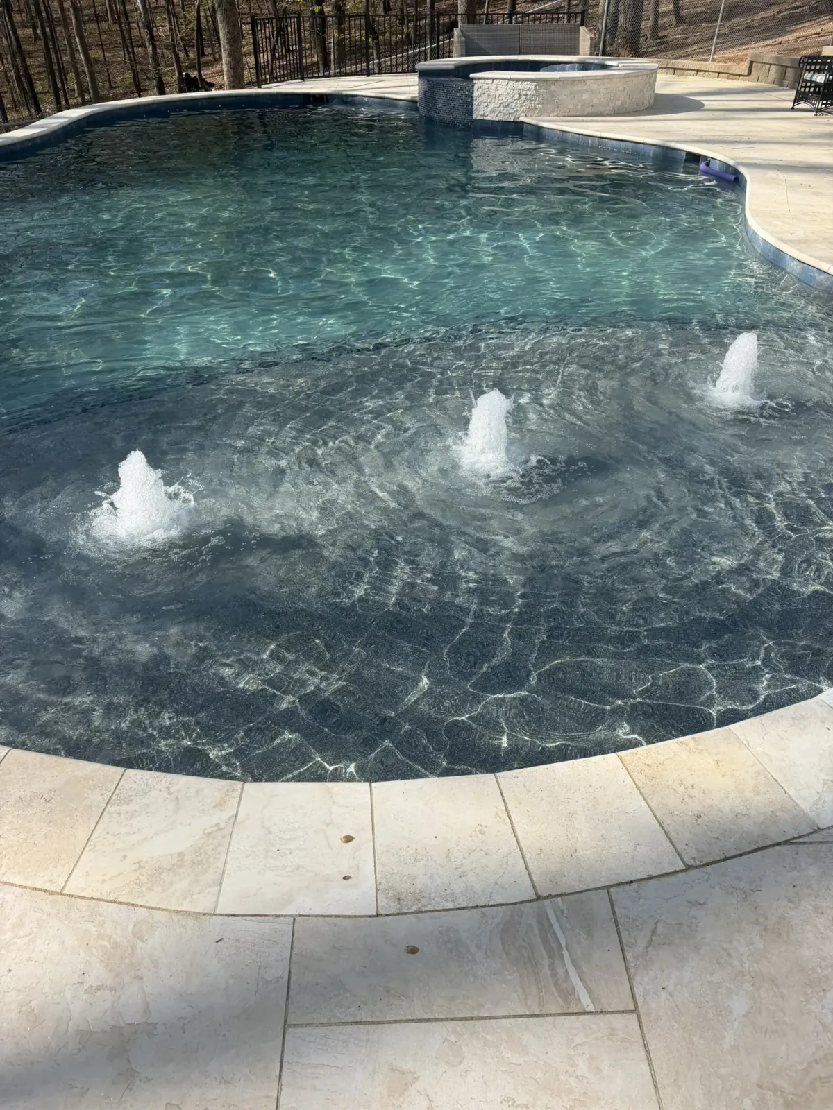 Finished RutherfordMade pool with bubbler fountains and a dark pebble finish